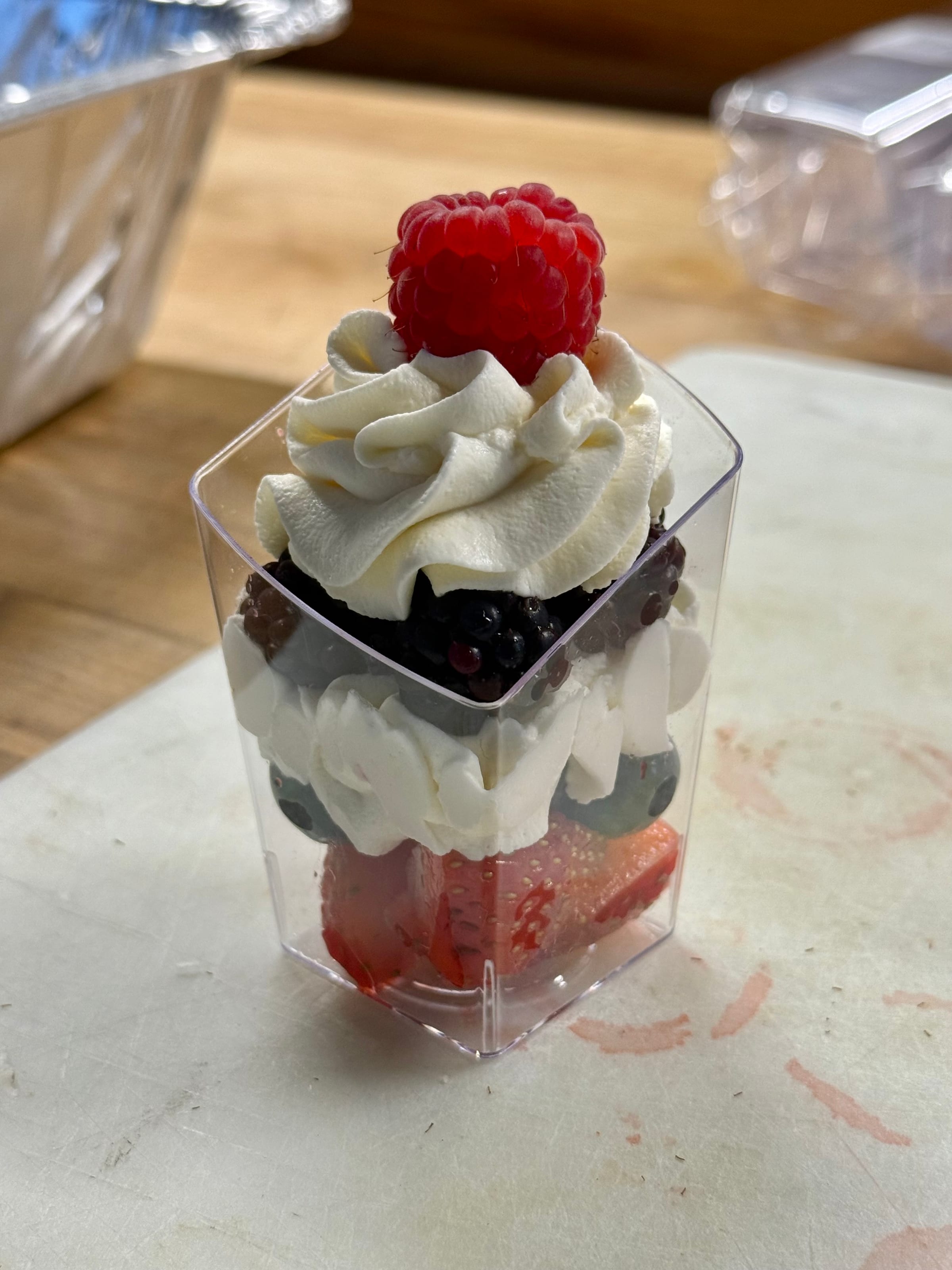 A mini berry trifle topped with whipped cream and a raspberry